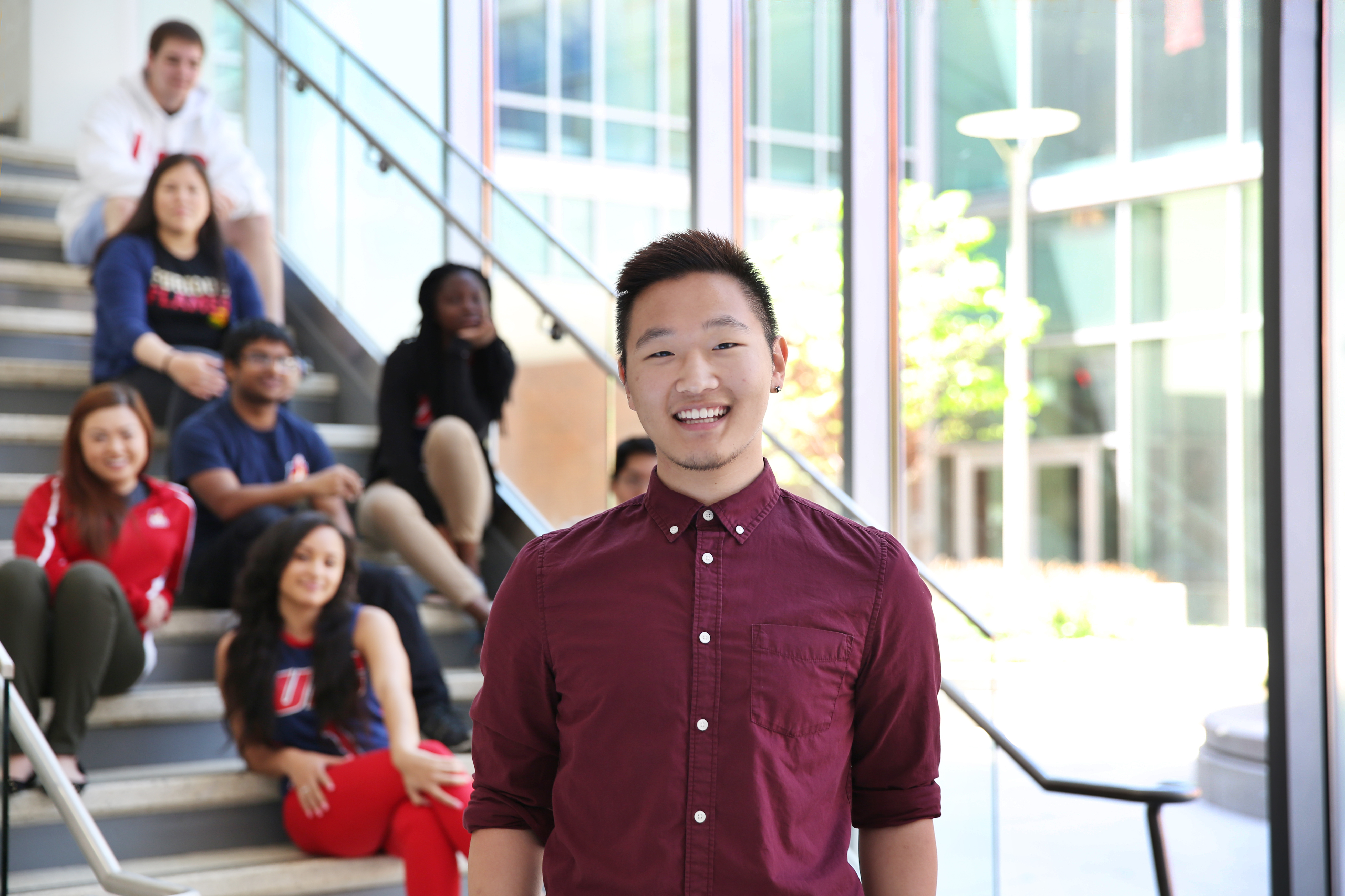 Student standing in front of staircase with other seated students